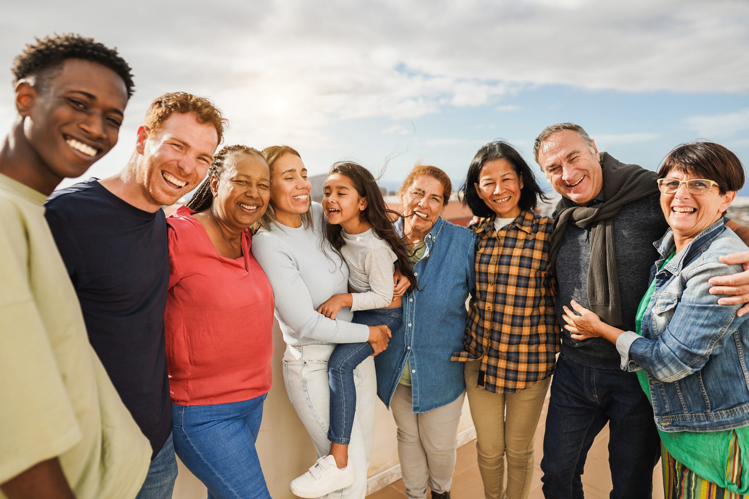 Group of multigenerational friends smiling in front of camera - Multiracial people of different ages having fun together - Main focus on latin mother and daughter faces